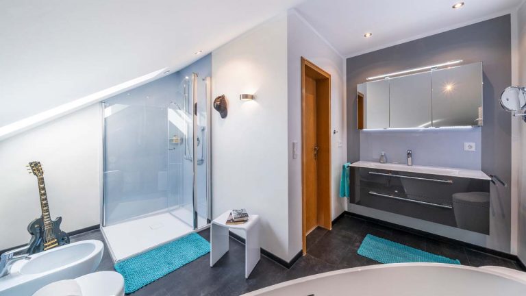 Referenzbad mit Dachschräge, Riegler-Wandpaneelen und freistehender Wanne